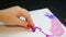 Female hand draws evening clouds on white paper with purple pastel