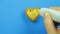 Female hand draws funny emoticons on heart shaped cookies on a blue background with brown icing from a tube