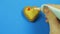 Female hand draws funny emoticons on heart shaped cookies on a blue background with red icing