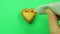 Female hand draws a heart-shaped cookie on a green background with a red tube frosting funny emoticons.