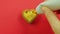 Female hand draws a heart-shaped cookie on a red background with caramel glaze from a tube funny emoticons