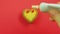 Female hand draws a heart-shaped cookie on a red background with a red tube frosting funny emoticons