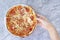 Female hand eating pizza on white stone background. Pizza at home, leisure, food and drink, people and holidays concept. Copy