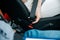 Female hand fastens seat belt. Close-up cut view of woman in white jeans holding black seatbelt. Road traffic safety