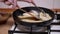 Female Hand Flips Chicken Chops on Hot Frying Pan with Wooden Spatula. Cook Meat