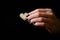 Female hand giving wooden heart on the black background