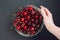 Female hand and glass bowl with juicy and red cherries