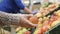 Female hand in glove picks fruits apples in basket in supermarket. Close-up
