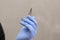 Female hand in gloves holds nail scissors. Manicure scissors, on a gray background. Manicurist. Close up