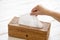 Female hand grabbing tissue paper in wooden box