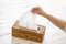 Female hand grabbing tissue paper in wooden box