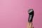 A female hand gracefully holds a male electric razor on a pink background. Minimalism