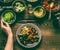 Female hand with healthy vegetarian bowl with various grilled vegetables, avocado and chickpea