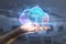 Female hand holding abstract glowing cloud hologram on blurry interior background. Cloud computing, future and data storage