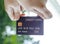 female hand holding a black credit card mockup with security chip embedded, Bokeh background