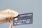 female hand holding a black credit card mockup with security chip embedded on a gray background with copy space