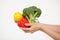 Female hand holding broccoli, a lemon and a red pepper