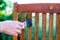 Female hand holding a brush applying varnish paint on a wooden garden chair