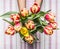 Female hand holding a Bunch of fresh bright tulips. Against the background striped tablecloth. top view close up