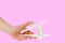 Female hand holding caliper on pink background. Copy space. Weight loss and slimming treatment