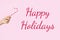 Female hand holding Christmas lollipop on a pink background