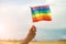 Female hand holding colorful rainbow lgbt flag against blue sky