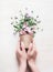 Female hand holding flowers pot with floral arrangements on white wooden background. Gardening and flowers still life