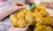 Female hand holding the fresh brown potato in the yellow net bag preparing for sell to customer in the food grocery supermarket