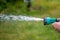 Female hand holding a garden hose, adjustable shower, spray. Summer garden watering.