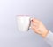 female hand holding a gray ceramic mug with a drink