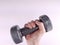 Female hand holding a grey dumbbell from lower side of the image, presenting strength and endurance while working out and
