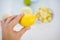 Female hand holding a lemon above slices of limes and lemons