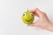 Female hand holding little Apple smile with Googly eyes. White background. Diet and weight loss concept