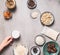 Female hand holding little jug with non dairy milk on concrete background with vegan gluten-free cake ingredients: cashew , almond