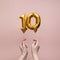 Female hand holding a number 10 birthday anniversary celebration gold balloon
