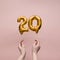 Female hand holding a number 20 birthday anniversary celebration gold balloon