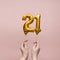 Female hand holding a number 21 birthday anniversary celebration gold balloon