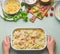 Female hand holding pasta casserole with tomato, bacon and cheese, top view.