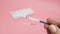 Female hand holding positive pregnancy test isolated on pink background. The abbreviation HCG on the blue bar means