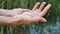 Female hand holding a rose quartz and amethyst crystal yoni eggs on river background. Women`s health, unity with nature