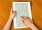 Female hand holding sheet with calculations on background wooden table.