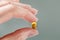 Female hand holding a small yellow capsule of nutritional supplement. Food supplement, vitamin D, omega, vitamin C.