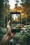 Female hand holding smartphone taking photos of beautiful scenery of forest mountains. Sustainable travel concept