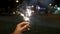 Female hand holding sparklers in the street. Close up of woman holding sparkler on the street. Closeup of Girl with