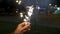 Female hand holding sparklers in the street. Close up of woman holding sparkler on the street. Closeup of Girl with