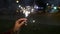 Female hand holding sparklers in the street. Close up of woman holding sparkler on the street. Closeup of Girl with