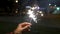 Female hand holding sparklers in the street. Close up of woman holding sparkler on the street. Closeup of Girl with