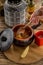 Female hand holding spoon of traditional Russian soup solyanka with smoked meat in clay pot on wooden table