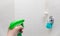 Female hand holding a spray bottle of cleaner directed at a shower ready to tackle grime