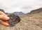 Female hand holding a stone with fossil leaves. Mountains in the background. Longyearbyen, Spitsbergen on Svalbard